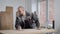 Adult bald worker man is grinding wooden board by hand sanding pad in a workshop in carpentry