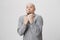 Adult bearded man with weard expression ready to fight holding his fists up over white background. Person tries to act