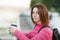 Adult beautiful redhead woman with bob haircut thinking drinking morning coffee in autumn city river pier