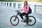 Adult beautiful redhead woman with bob haircut thinking drinking morning coffee posing on bicycle in autumn city river pier