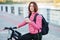 Adult beautiful redhead woman with bob haircut thinking drinking morning coffee posing on bicycle in autumn city river pier