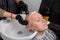 Adult beautiful woman of European appearance barbershop client in the process of washing hair before cutting or dyeing