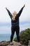 Adult blonde female woman raises her arms up giving peace sign on Wedding Rock in Patrick`s Point State Park in Trinidad,