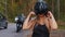 Adult blonde woman motorbike rider fixes her helmet and looking in the camera
