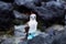 Adult blue-footed booby perched on rock staring intently with red painted ghost crabs in soft focus