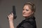 Adult business woman with black gun on a gray background