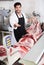 Adult butcher is demonstraiting meat to clients