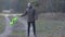 Adult Caucasian man in autumn clothes shaking green vest as standing on forest road, throwing it away and walking to
