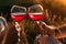 Adult caucasian man and woman hands toasting red wine glasses in summer at sunset. Toast and clinking clatter glasses.