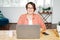 Adult charming brunette woman in glasses plus size body positive working with laptop at home