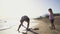 An adult and child engage in digging sand at a sunlit beach, representing a family vacation moment with gentle ocean