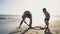 An adult and child engage in digging sand at a sunlit beach, representing a family vacation moment with gentle ocean