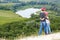 Adult and child standing on a mountaintop near river.