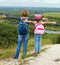 Adult and child standing on a mountaintop near river.