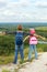 Adult and child standing on a mountaintop near river.