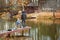 Adult and child on a wooden pier, fishing bridge. Autumn park. Fallen leaves, sunny day, natural background.