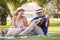 Adult Couple outdoors enjoying a summery day looking happy - man playing guitar woman laughing a lot having fun - concept of