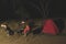 Adult couple relaxing in camping site by night. Adventure in National Park, South Africa. Burning camp fire and tent in the backgr