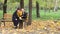 An adult couple sits on a bench in a forest park, talks and laughs, a man and a woman communicate in nature on a sunny