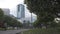 Adult couple walking along alley with flowering apple trees in spring against blue cloudy sky and modern buildings