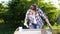 Adult crafts woman painting wooden planks with white paint in summer orchard