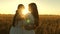 Adult daughter in arms of her mother in a field in the rays of the sun. Mom gently hugs daughter against backdrop of a