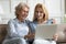 Adult daughter help to elderly mother with laptop usage