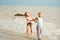 Adult daughter and mother spinning on the sea shore holding hands