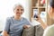 Adult daughter photographing senior mother at home