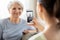 Adult daughter photographing senior mother at home