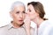 Adult daughter whispering to senior mother