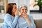 Adult daughter whispering to senior mother at home