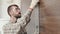 An adult engineer in uniform measures a brick wall with a level, an architect in a protective helmet checks the data of