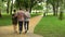 Adult father walking with daughter and son in park, hugging and talking, family