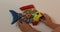 Adult female hands hanging a multicolored talavera ceramic fish against a white wall