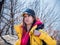 Adult female hiker wearing yellow jacket and black sport hat putting her backpack on.