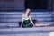 Adult female Hispanic classical ballet dancer in green and black tutu with coins, legs wide open in the middle of stairs