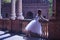 Adult female Hispanic classical ballet dancer making figures leaning on a stone balustrade, wearing a white tutu