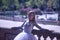 Adult female Hispanic classical ballet dancer making figures leaning on a stone balustrade, wearing a white tutu