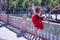 Adult female Hispanic classical ballet dancer in red tutu doing figures next to a stone railing in the middle of a plaza on a