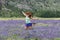 Adult female jumps in a field of purple lupine wildflowers in the June Lake Loops in the Eastern Sierra mountains of California.