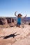 Adult female jumps and smiles at a scenic overlook in Utah Canyonlands National Park on a sunny day. Concept for freedom,