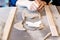 Adult female potter master cutting the clay on table.