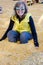 Adult female sits down in a corn pit with yellow corn kernels