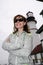 Adult female wearing a hoodie poses with arms crossed in front of Portland Head Lighthouse