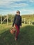 Adult female woman on farm carrying holding wicker basket and picking fresh apples harvest.