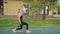 Adult fitness woman doing walking lunges with dumbbells on a sports ground