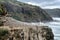 Adult gannets sitting on cliff of Pacific Ocean with waves in ba