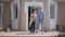 Adult grandson and his grandmother holding bouquet of tulips overlook the porch of the big house. The granny telling