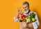 Adult grey haired man with beard with paper bag full of various healthy vegetarian goods gestures OK sign